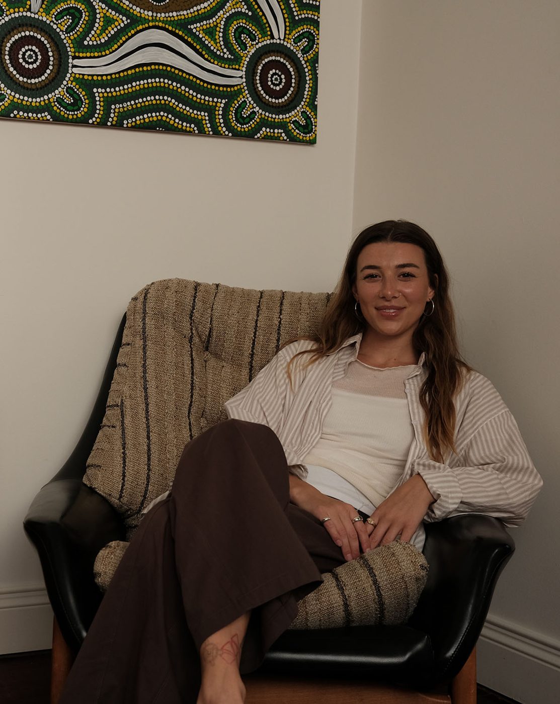Charli sitting in a cosy armchair in her therapy room