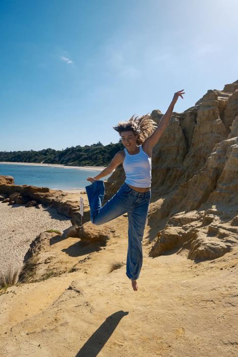 Charli leaping with joy on the sandstone cliffs by the beach